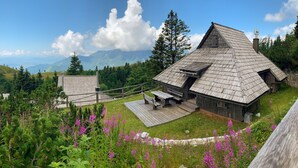 Une cabane en bois rustique, dotée d’un toit en pente, entourée d’une terrasse en bois et de bancs.