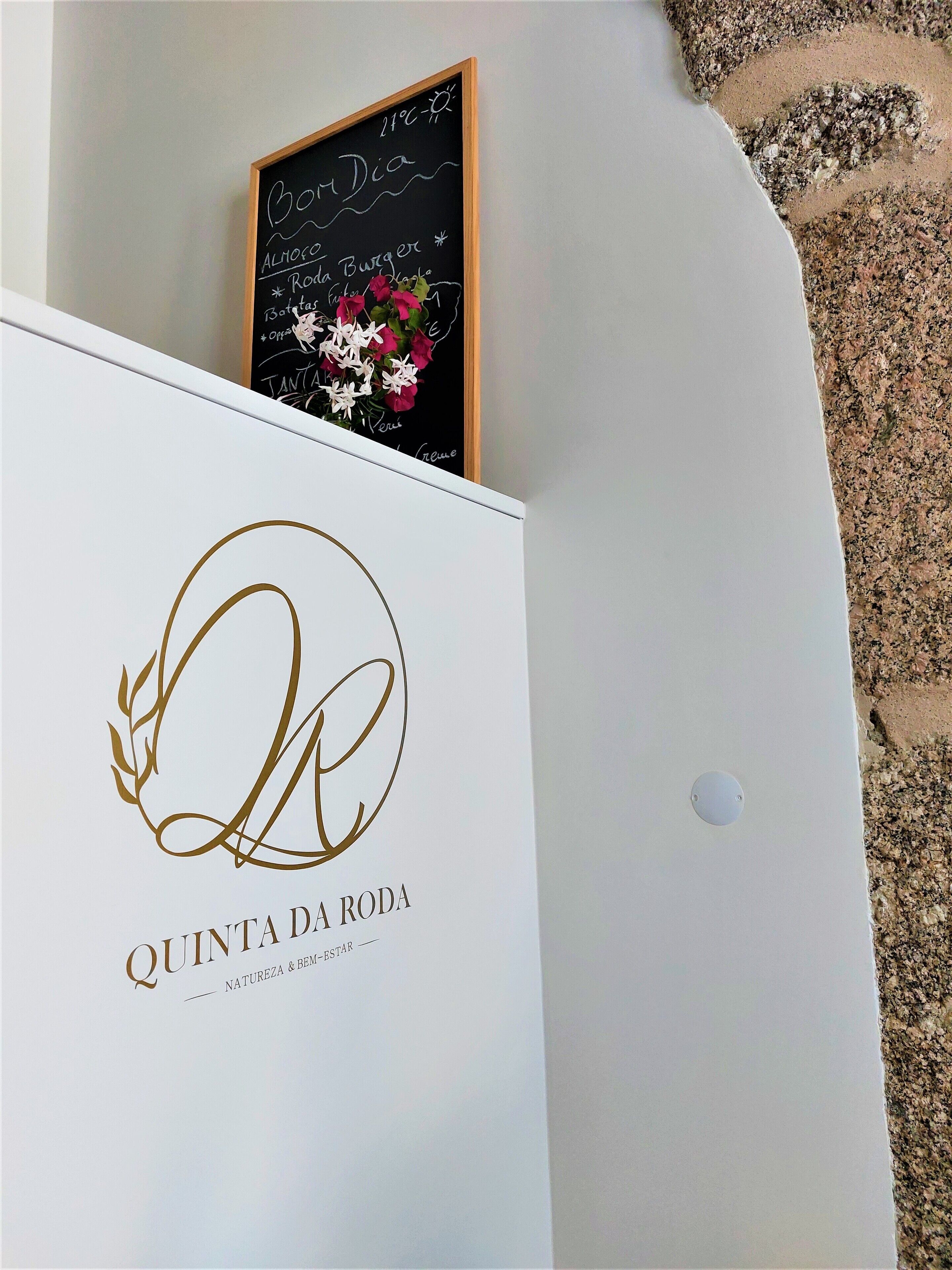 A sign with a logo and text for "Quinta da Roda" and a chalkboard menu above it.