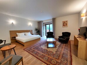 A hotel room with a large bed, a desk, a chair, a coffee table, and a carpeted floor. - Quinta da Roda - Nature and Wellness (Vila Verde)
