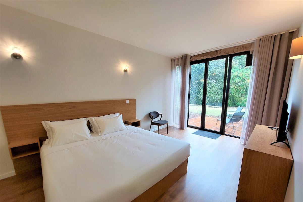 A hotel room with a large bed, a desk, and a view of the outdoors.
