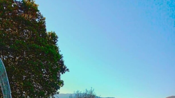 A swimming pool with clear blue water, surrounded by greenery and mountains in the background. - Quinta da Roda - Nature and Wellness (Vila Verde)