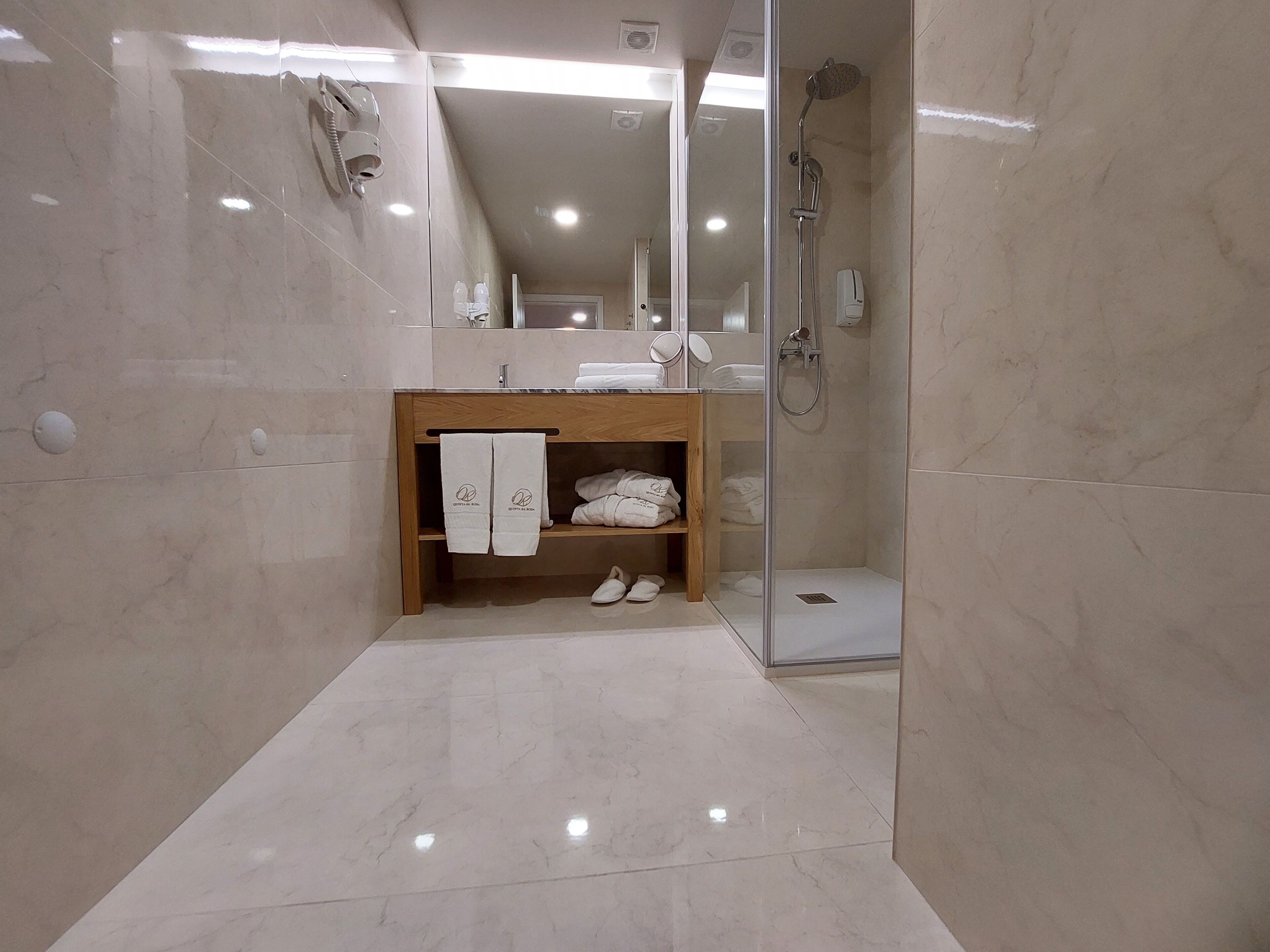 A modern bathroom with a glass-enclosed shower, a wooden vanity with a mirror, and neatly folded towels.