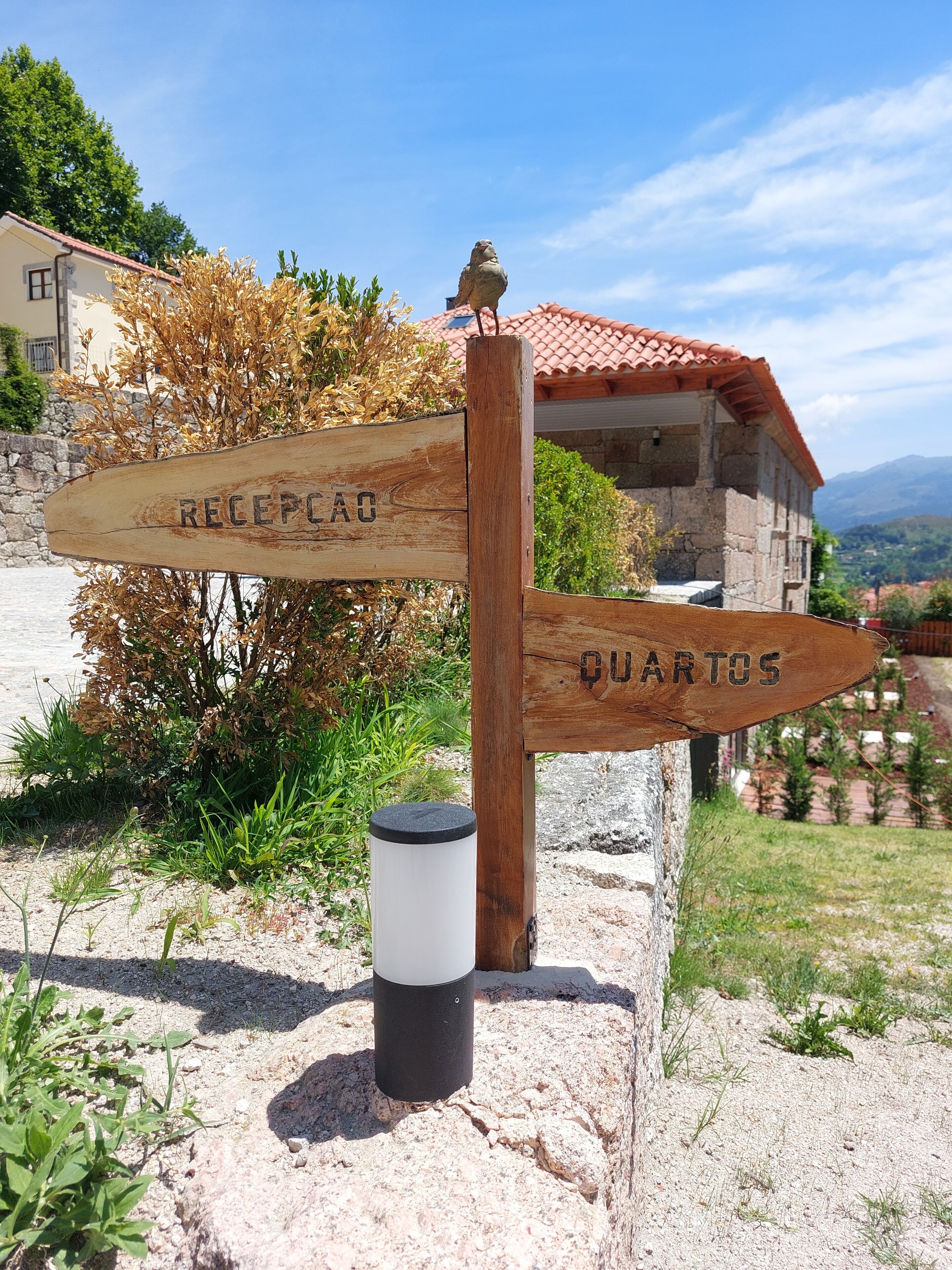 A wooden signpost with directions to 'Recepca' and 'Quartos'.