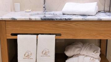 Een badkamer met een marmeren wastafel, een houten wastafelmeubel en twee handdoeken met de branding 'Quinta da Roda'.