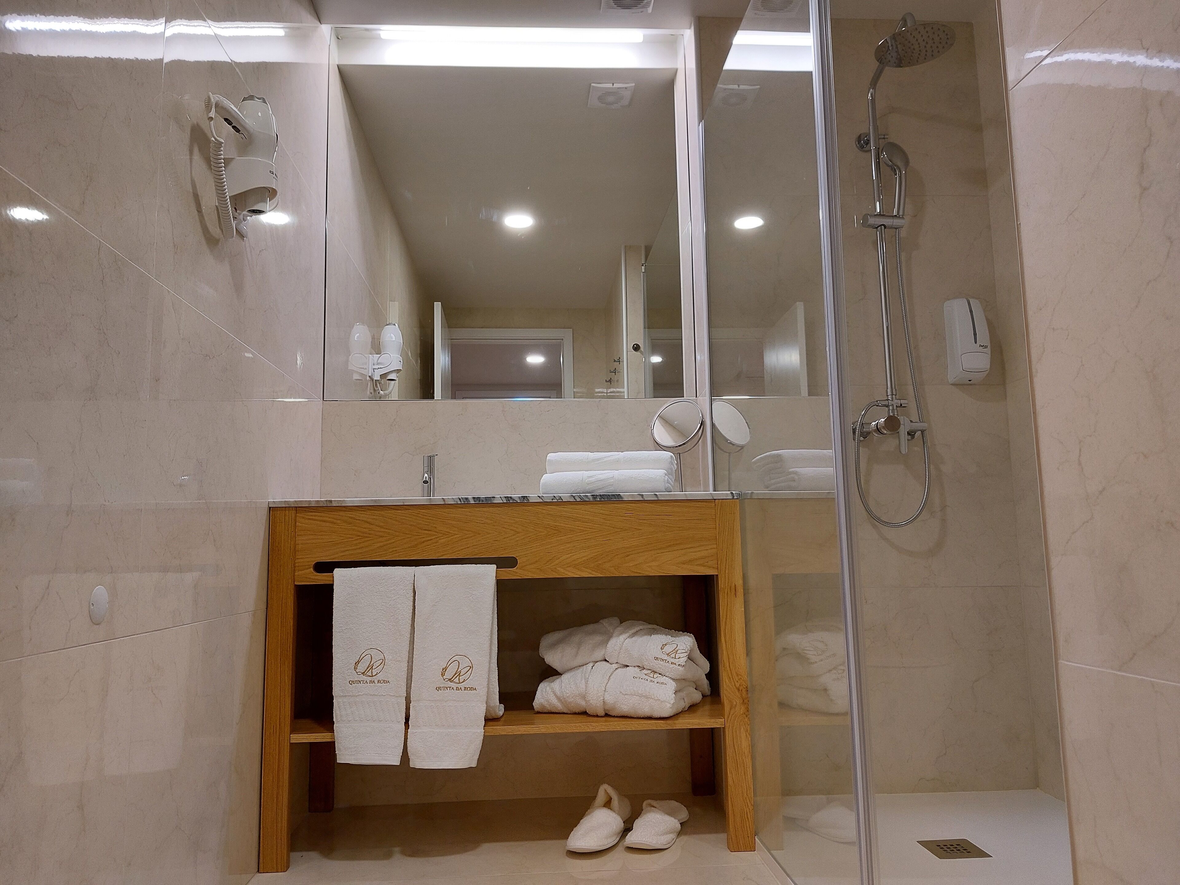 A modern bathroom with a wooden vanity, a glass shower enclosure, and a mirror above the vanity.