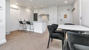 Una cocina moderna con armarios blancos, una isla central con taburetes y una mesa de comedor con sillas.