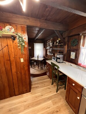 Une cuisine rustique avec des murs en bois, une table à manger et un réfrigérateur.