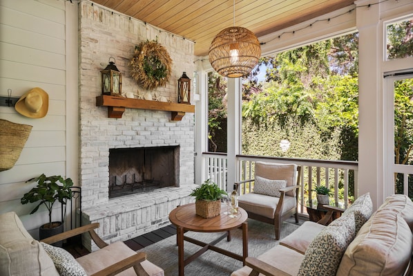 A cozy outdoor seating area with a fireplace, wicker basket, and potted plants.