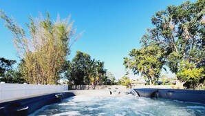 A hot spring area with a clear pool, surrounded by trees and a white fence. - Super close to the beach. Private Hot Tub Backyard (Naples)