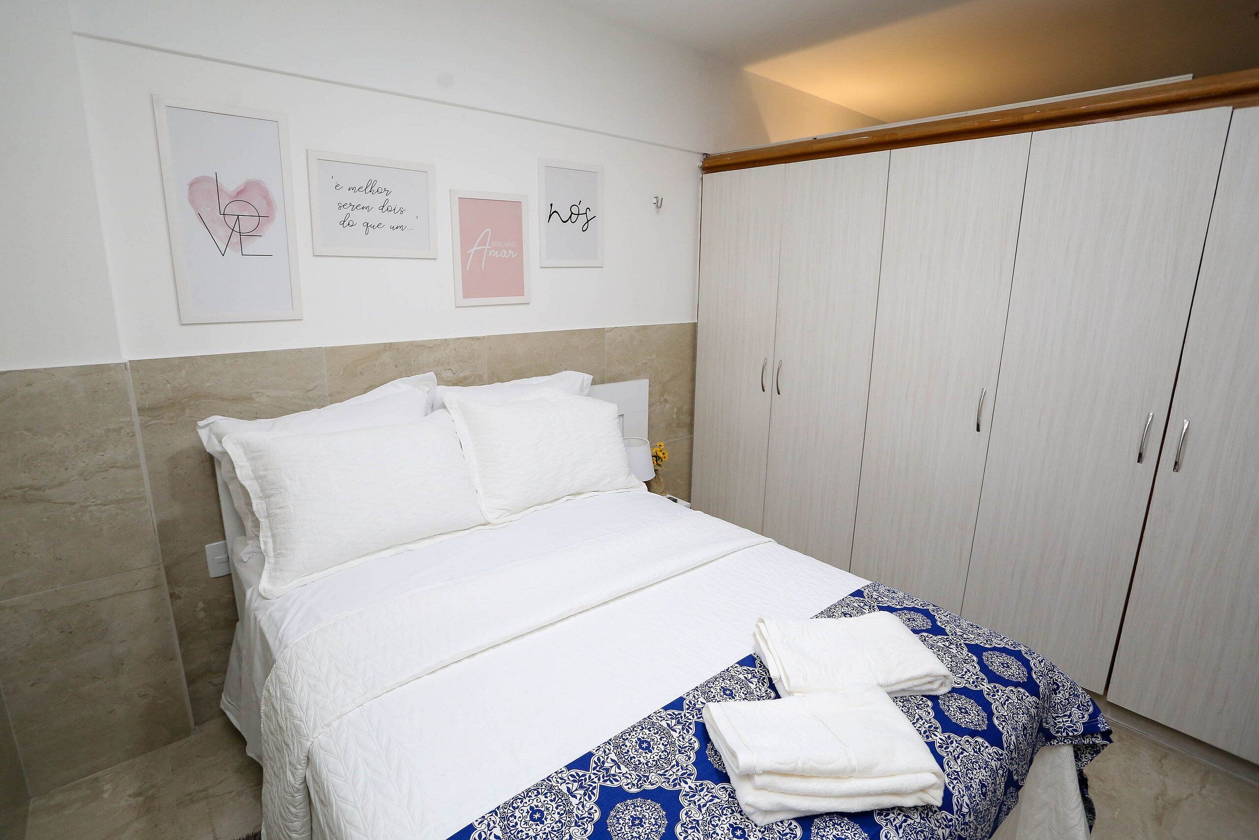 Un dormitorio con cama, armario y decoración en la pared.