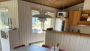 A dining area with a striped tablecloth, red chairs, and a wooden ceiling. - Cozy cottage 250 m. from the beach. (Nykøbing sj.)