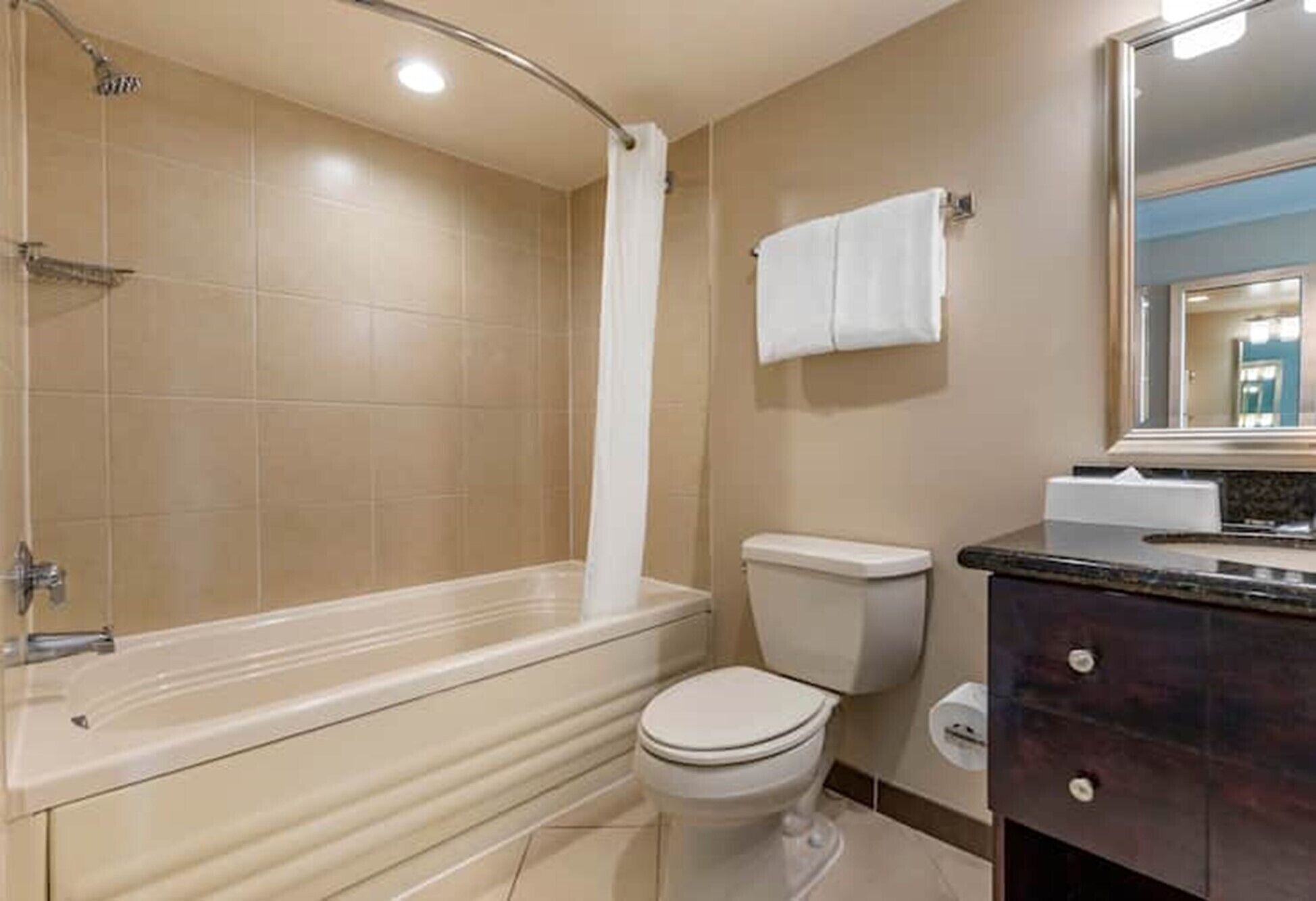 Et badeværelse med badekar, toilet og håndvask med spejl.