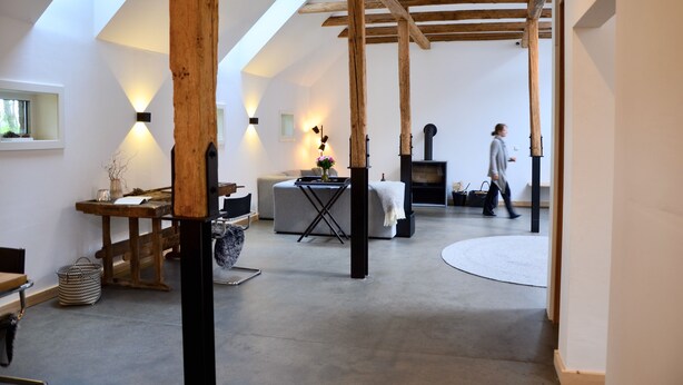 Un loft spacieux avec des poutres apparentes, une cheminée et une grande fenêtre.