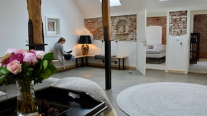 Un loft moderne avec des murs en briques apparentes, une verrière, un coin lecture confortable et une grande fenêtre.