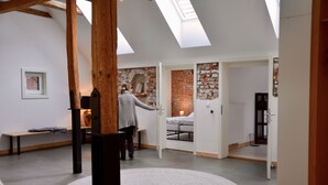 Un intérieur moderne agrémenté de puits de lumière, de murs en briques apparentes et d’un tapis rond.