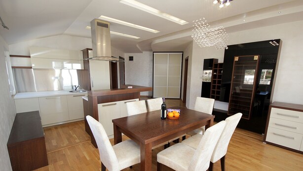 Een moderne keuken met een houten eettafel, witte stoelen en een fruitschaal.