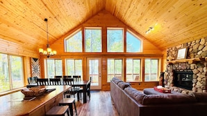 A wooden cabin interior with a dining area, kitchen, and seating area. - Pet-Friendly Lakeside Cottage w/ Kayaks and Canoe! (Stone Lake)