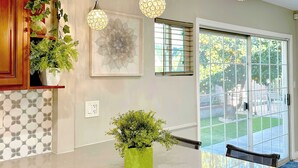 Una cocina moderna con una isla grande, luces colgantes, una planta verde y una ventana con vistas al exterior.