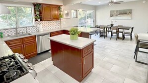 Una cocina moderna con una isla central, armarios de madera y una zona de comedor con mesa y sillas.