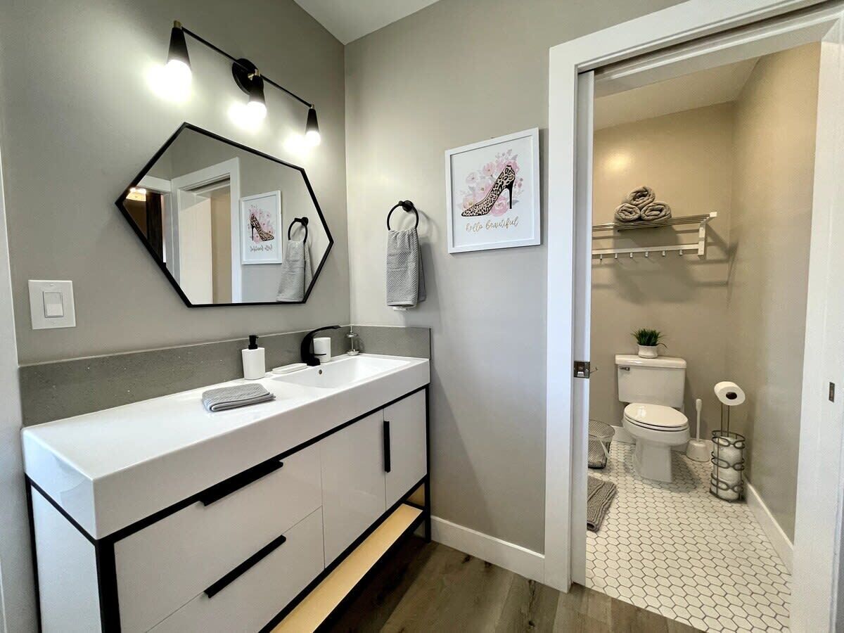 Une salle de bain moderne avec un meuble-lavabo blanc, un grand miroir et des toilettes.