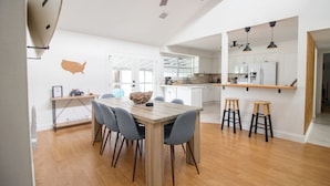 A modern kitchen with white cabinets, a wooden dining table, and bar stools. - *Update * New Game Room, near Navy Base and Beach! (Atlantic Beach)