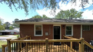 A single-story brick building with a front porch, a black door, and a small window. - 3 BR renovated home, near downtown Raleigh, privacy fenced backyard! (Raleigh)