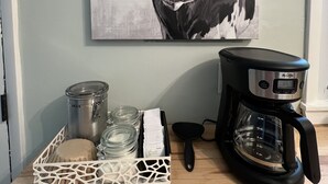 A coffee maker, a glass jar, and a container on a wooden table. - 3 BR renovated home, near downtown Raleigh, privacy fenced backyard! (Raleigh)