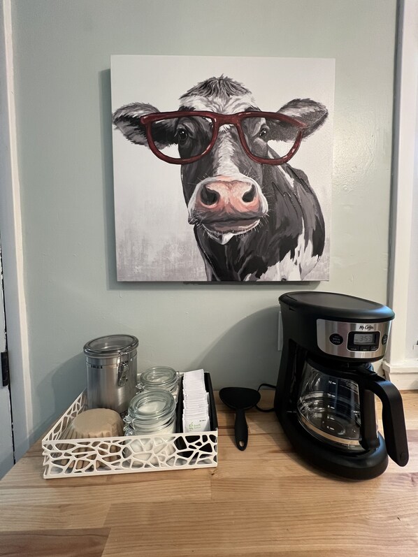 A coffee maker, a glass jar, and a container on a wooden table.