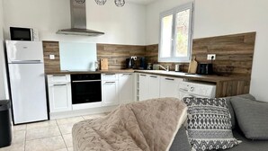 Une cuisine moderne avec des appareils électroménagers blancs, un mur d’accent en bois et une fenêtre donnant sur un espace verdoyant.