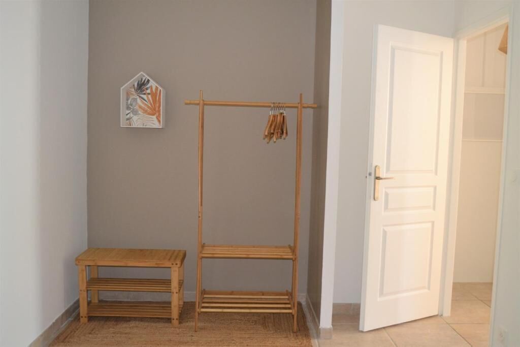 A room with a wooden bench, a wooden drying rack, and a white door.