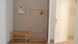 Une pièce avec un banc en bois, un étendoir en bois et une porte blanche.