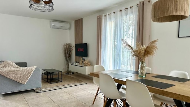 Un salon moderne comprenant un canapé, une table à manger, des chaises et un téléviseur.