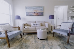 Relax in this inviting living room with a comfortable sofa, two armchairs, and a round ottoman.