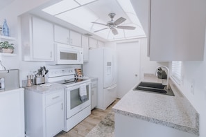 A modern kitchen with white cabinetry, a microwave, a refrigerator, and a stove.