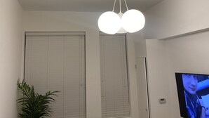 Una sala de estar con una lámpara de techo, un televisor y una planta en maceta.