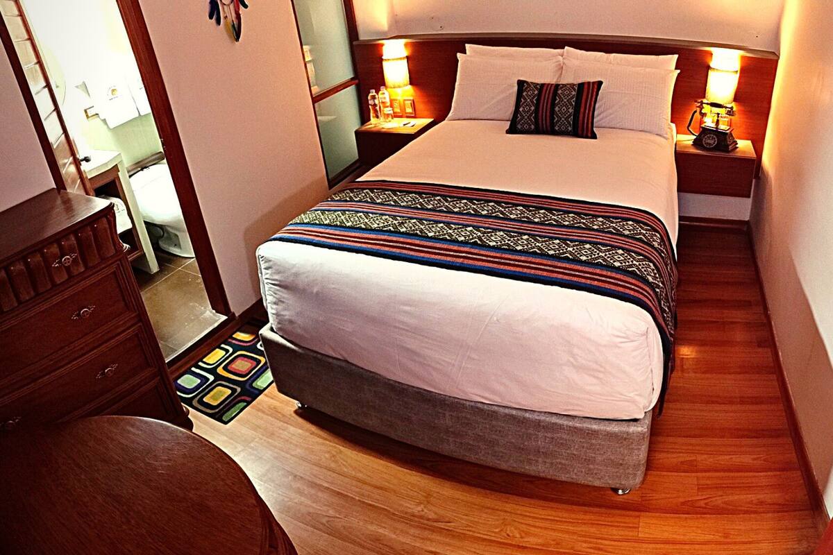 Une chambre d’hôtel avec un lit, des tables de chevet, une commode et un plancher en bois.