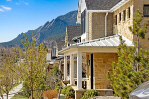 A residential building with stone exterior walls, a covered porch, and a view of mountains in the background. - Central Sundance location, steps to Sanitas trail and walk to downtown Boulder (Boulder)
