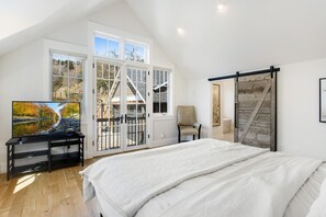 A bedroom with a large bed, a TV on a stand, a chair, and a sliding barn door. - Central Sundance location, steps to Sanitas trail and walk to downtown Boulder (Boulder)