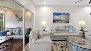 Ein modernes Wohnzimmer mit einem Glastisch, zwei Sofas und einem Gemälde an der Wand.