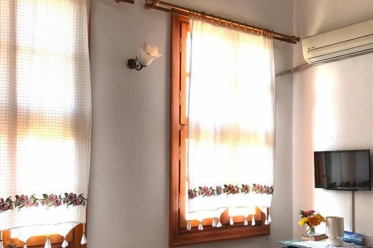 Une chambre avec deux lits, un bureau, une télévision et une fenêtre avec des rideaux.