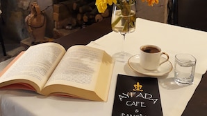 Une table avec un livre ouvert, une tasse de café, un verre d’eau et un menu.