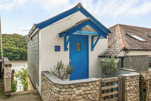 Un petit bâtiment d’un seul étage, avec une porte bleue et une enseigne indiquant qu’il s’agit du « Beach Hut Malpas ».