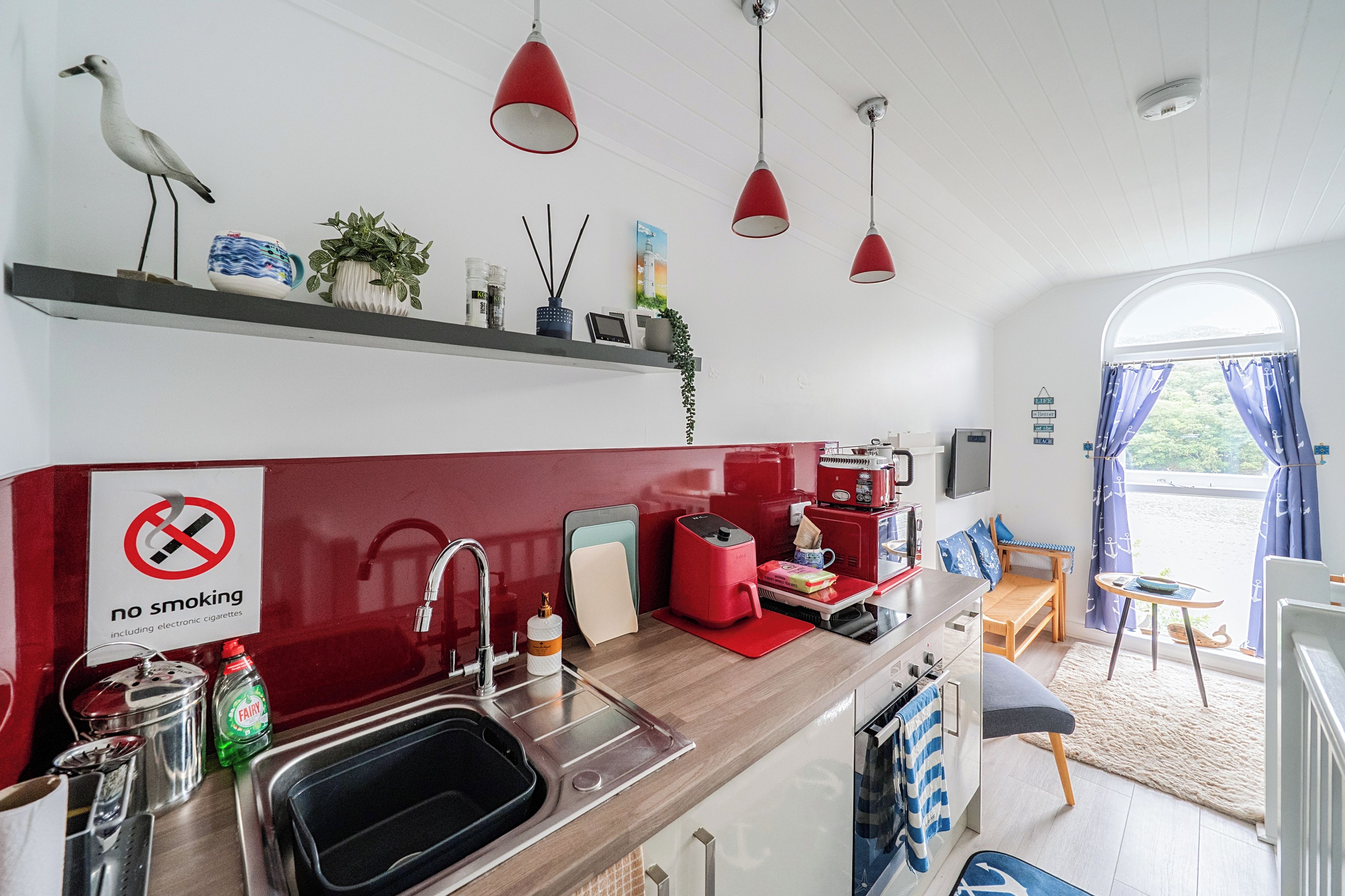 A kitchen with a no smoking sign, a coffee machine, and a view of the outside.
