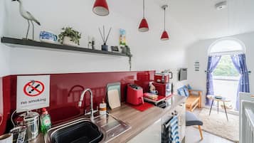 A kitchen with a no smoking sign, a coffee machine, and a view of the outside.