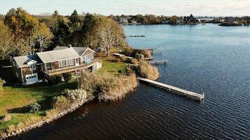 A lakeside property with a house, dock, and surrounding vegetation.