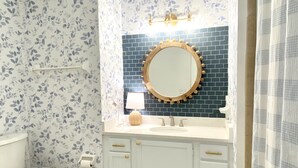 A bathroom with a toilet, a sink with a mirror, and a shower curtain.