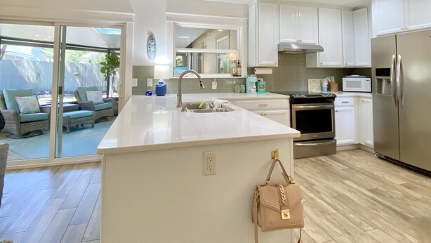A modern kitchen with a large island, stainless steel appliances, and a view to a patio area.