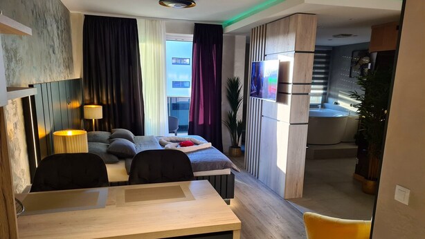Een moderne hotelkamer met een bed, een bureau, een televisie en een badkamer zichtbaar door een geopende deur.