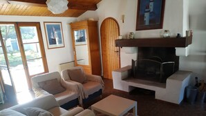 A cozy living room with a fireplace, comfortable seating, and framed nautical paintings. - Beautiful Vendée house 50 meters from the beach, sleeps 2 to 10, depending on the season. (La Guérinière)