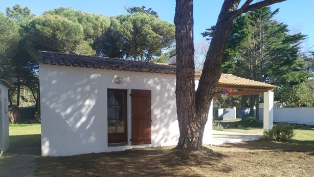 A small white building with a tiled roof, a wooden door, and a window. - Beautiful Vendée house 50 meters from the beach, sleeps 2 to 10, depending on the season. (La Guérinière)